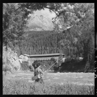 Mann am Fluss am Fischen, Brücke im Hintergrund