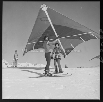 Mann auf Ski, Frau mit Hängegleiter