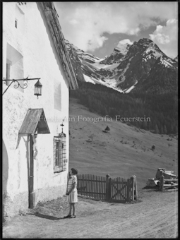 Mädchen vor Haus, Berge im Hintergrund