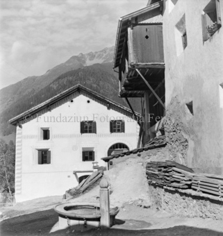 Hausfassade mit hölzernem Erker, Berglandschaft im Hintergrund, Bezeichnung Hülle: Guarda, neue Aufnahmen