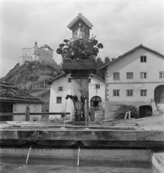 Blumen und Heiligenschrein auf dem Brunnen, Häuser im Hintergrund, Tarasp, Bezeichnung Hülle: Motive Sommer / Winter