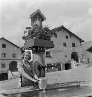 Blumen und Heiligenschrein auf dem Brunnen, Häuser im Hintergrund, Tarasp, Bezeichnung Hülle: Motive Sommer / Winter