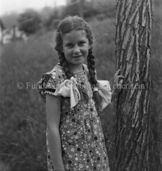 Mädchen in gepunktetem Kleid, Schleifen an Zöpfen