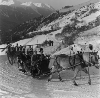 Festliche Pferdeschlitten auf verschneiter Bergstrasse
