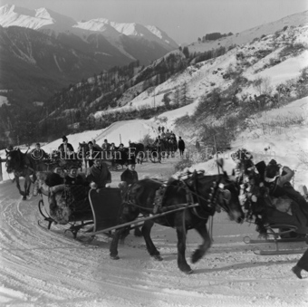 Festliche Pferdeschlitten auf verschneiter Bergstrasse
