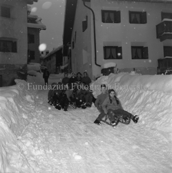 Kinder schlitteln verschneite Dorfstrasse runter, Schneefall