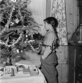 Mädchen neben geschmücktem Weihnachtsbaum