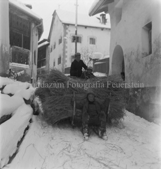 Kinder transportieren mit Schlitten Stroh über verschneite Dorfstrasse