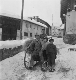 Kinder transportieren mit Schlitten Stroh über verschneite Dorfstrasse