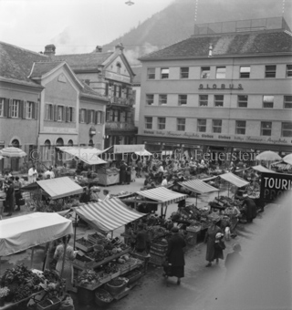 Marktstände und Besucher auf Platz, «Globus» und «Neue Bündner Zeitung» im Hintergrund