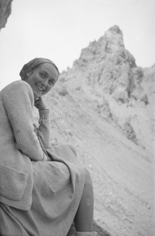 Frau sitzend, Berggipfel im Hintergrund