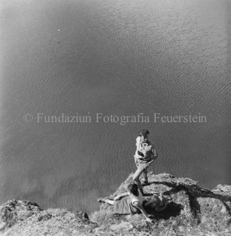 Mann und Frau sitzend auf Fels, unten Bergsee