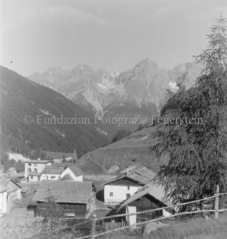 Bergdorf, hinten Wald und Berge