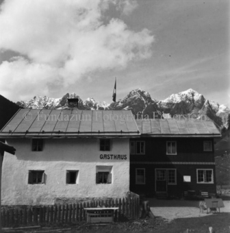Gasthaus, gehisste Schweizerflagge, Berge im Hintergrund