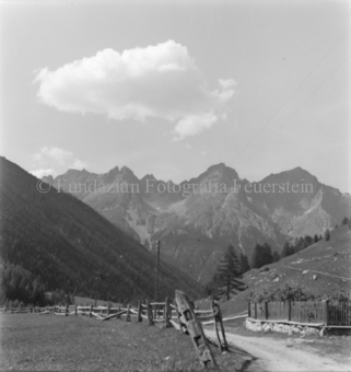 Feldweg und Holzzäune, Bergpanorama, Wolke