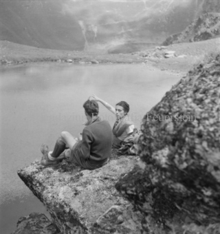 Mann und Frau auf Fels über Bergsee