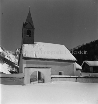 Verschneite Kirche mit Aussenmauer und Tor