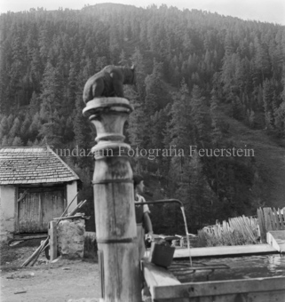 Frau an Brunnen mit Bärenskultpur