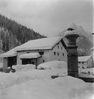 Verschneites Haus, Strasse und Brunnen schneebedeckt