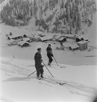 Zwei Skitourengänger im Schnee, blicken auf Dorf im Tal