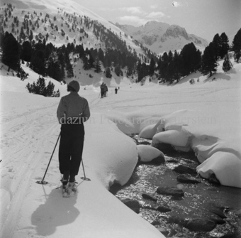 Skitourengängerin bei Piste neben Bergabach, andere voraus