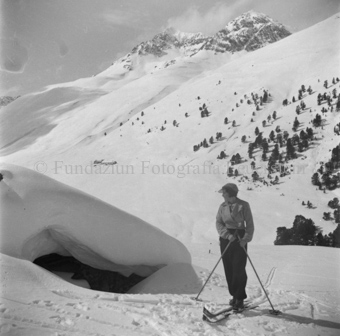 Skitourengängerin, blickt auf Höhle unter Schneewehe
