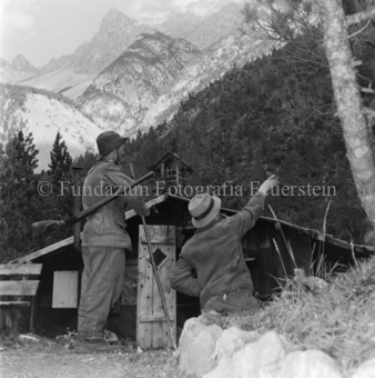 Zwie Jäger vor Hütte, in den Wald schauend