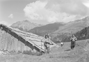 Wanderer neben Berghütte mit tiefem Dach
