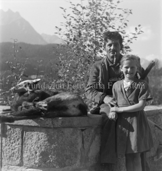 Geschossene Gämse auf Seinmauer, Jäger und Mädchen