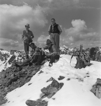 Vier Bergsteiger auf Berg, zwei stehend, zwei sitzend