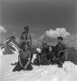 Vier Bergsteiger neben Ausürstung, Bergpanorama