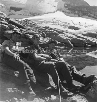 Drei Bergsteiger sitzend, neben Gletscher