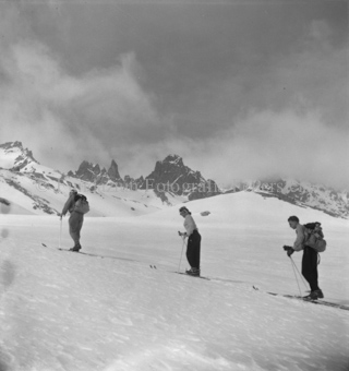 Zwei Skitourengänger, eine Skitourengängerin den Hang hinauf gehend, Bergzacken