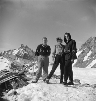 Mann und zwei Frauen vor Gletscher, Ski auf Stein