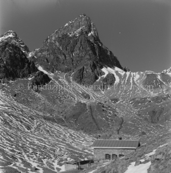 Skihütte vor Berggipfel, nur vereinzelt Schnee