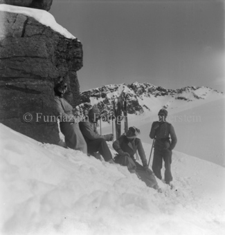 Skitourengänger ausruhend vor Felswand, Ski im Boden
