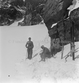 Skitourengänger ausruhend vor Felswand, Ski im Boden