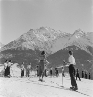 Skifahrerinnen in unterschiedliche Richtungen fahrend, einige in Reihe stehend, hinten Berg