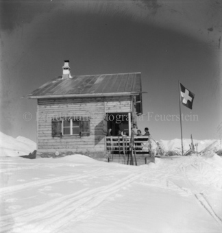 Skihütte mit Gruppe auf Veranda, Schweizer Fahne
