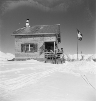 Skihütte mit Gruppe auf Veranda, Schweizer Fahne