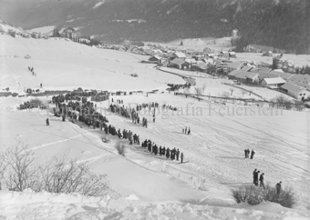 Zuschauer vor Ziel, im Hintergrund verschneites Dorf