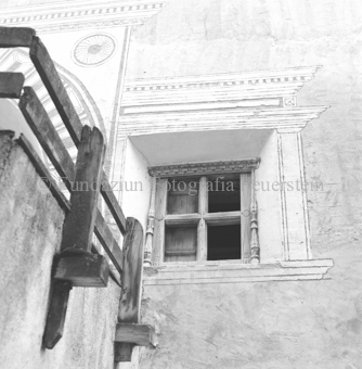 Verziertes Fenster neben Holzgeländer