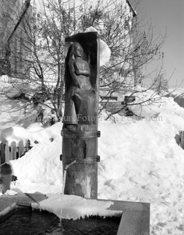 Brunnenstatue «Duonna Lupa» vor Kirche im Winter
