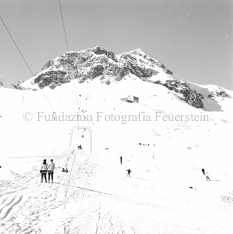Skifahrer auf Schlepplift Schlivera auf dem Weg zur Berghütte Chamanna Naluns