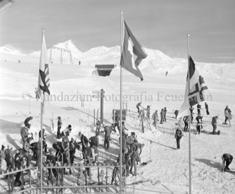 Skifahrer vor der Berghütte, gelagerte Ski, Fahnen im Vordergrund