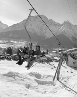 Snowboarder Sessellift in Ftan mit Dorfansicht und Kirche, parkierte Autos