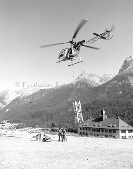 Helikopter mit Bauelement für Seilbahnmast, beim Bahnhof Scuol, Sommer