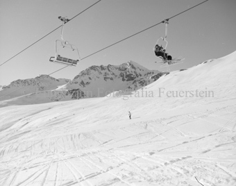 Sessellift mit Skifahrer, Skipiste und Berglandschaft