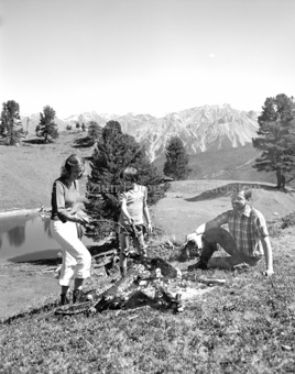 Familie mit Kind am Lagerfeuer bei Bergsee