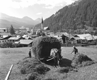 Bauern laden Heu auf Pferdewagen, Dorf Santa Maria mit Kirche im Hintergrund